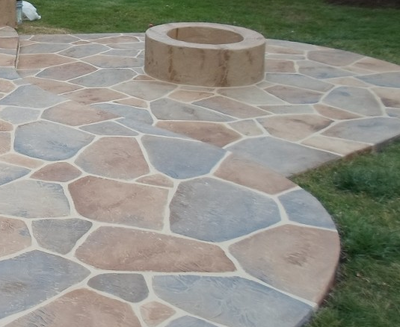 Multi-colored stone patio with built in round firepit.